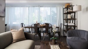 A modern living room with a dining table, two sofas, a bookshelf, and a potted plant. - Gracious 2 Bed 2 Bath Apartment with Free Parking (Arlington)