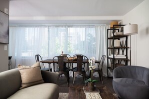 A modern living room with a dining table, two sofas, a bookshelf, and a potted plant. - Gracious 2 Bed 2 Bath Apartment with Free Parking (Arlington)
