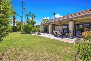 A residential property with a covered patio, outdoor seating, and a well-maintained lawn. - Rose Garden Escape - Stylish 2 Bedroom Condo (Palm Springs)