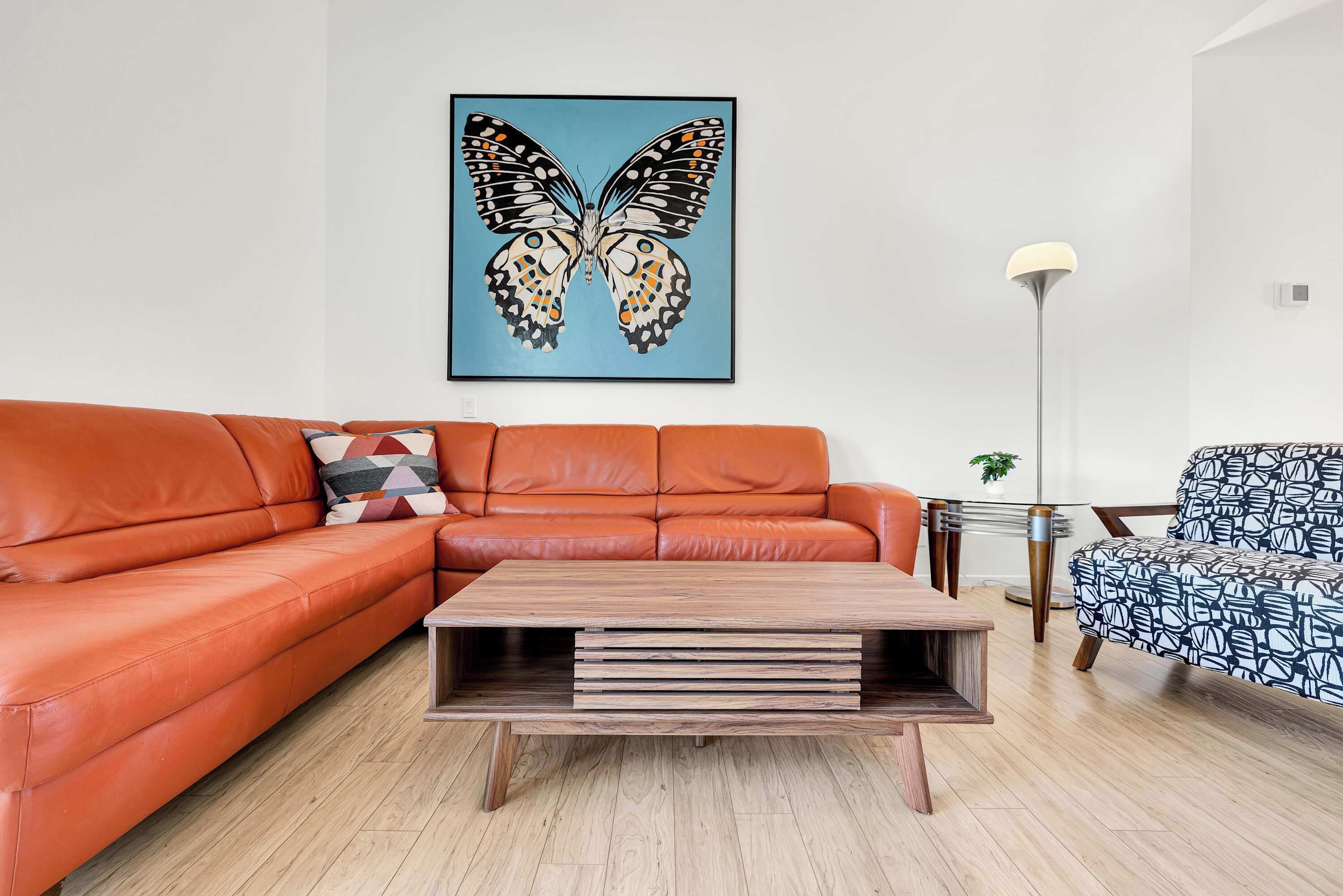 A living room with a sofa, a coffee table, a floor lamp, and a chair.