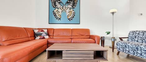 Una sala de estar con un sofá, una mesa de centro, una lámpara de pie y un sillón.