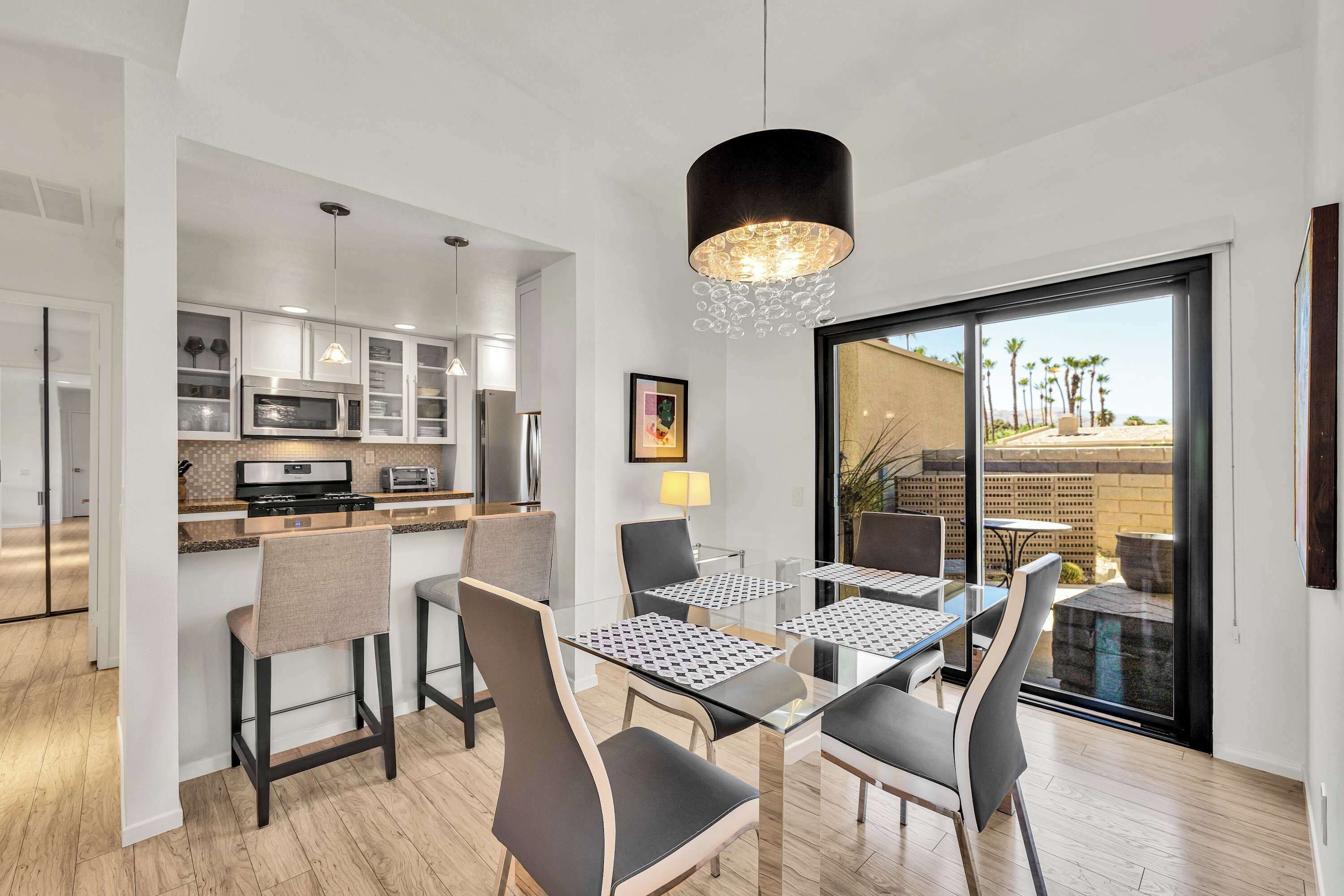 Una cocina moderna con electrodomésticos integrados y un comedor con mesa y sillas de vidrio.