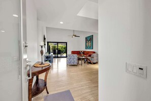 A modern living room with a sofa, chairs, a coffee table, and a dining area with a table and chairs. - Rose Garden Escape - Stylish 2 Bedroom Condo (Palm Springs)