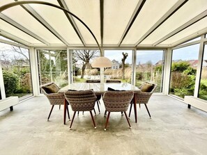 A conservatory with a glass enclosure, a round table, wicker chairs, and a lamp. - Deluxe Waterfront Bungalow With Jetty (Makkum)