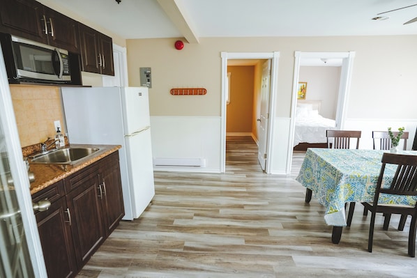 A kitchen with dark wooden cabinets, a white refrigerator, and a microwave.