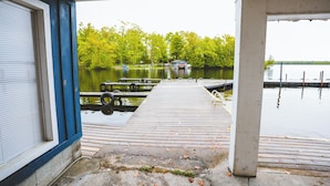 A wooden dock extending into a calm lake, surrounded by trees.