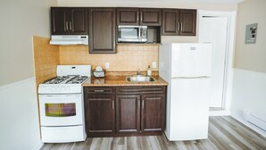 A kitchen with dark wooden cabinets, a white stove, a microwave, and a white refrigerator.