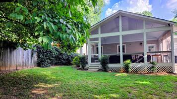 A house with a covered porch, a fenced yard, and a well-maintained lawn.