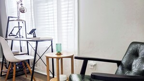 Ein modernes Wohnzimmer mit einer Ledersofa, einem gewebten Hocker, einem kleinen runden Tisch und einem Sessel.