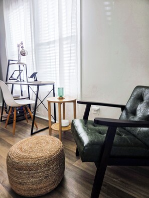 Un salon moderne avec un canapé en cuir, un pouf en fibres tressées, une petite table ronde et un fauteuil.