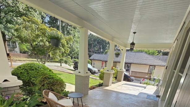 Ein überdachter Patio-Bereich mit Gartenmöbeln und Blick auf eine Wohnstraße.