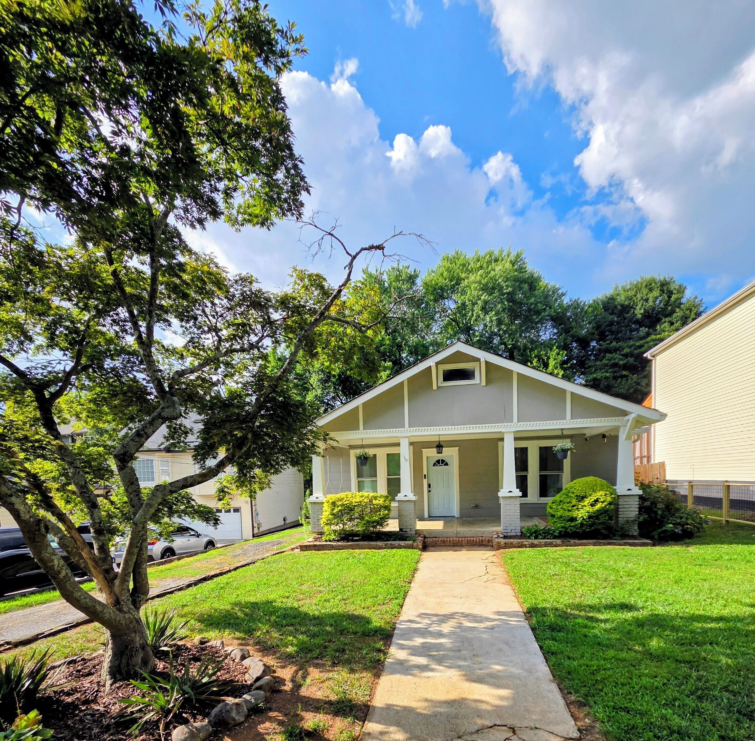A single-story house with a front porch, a driveway, and a well-maintained lawn.
