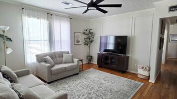 A living room with a sofa, a coffee table, a TV, and a ceiling fan.