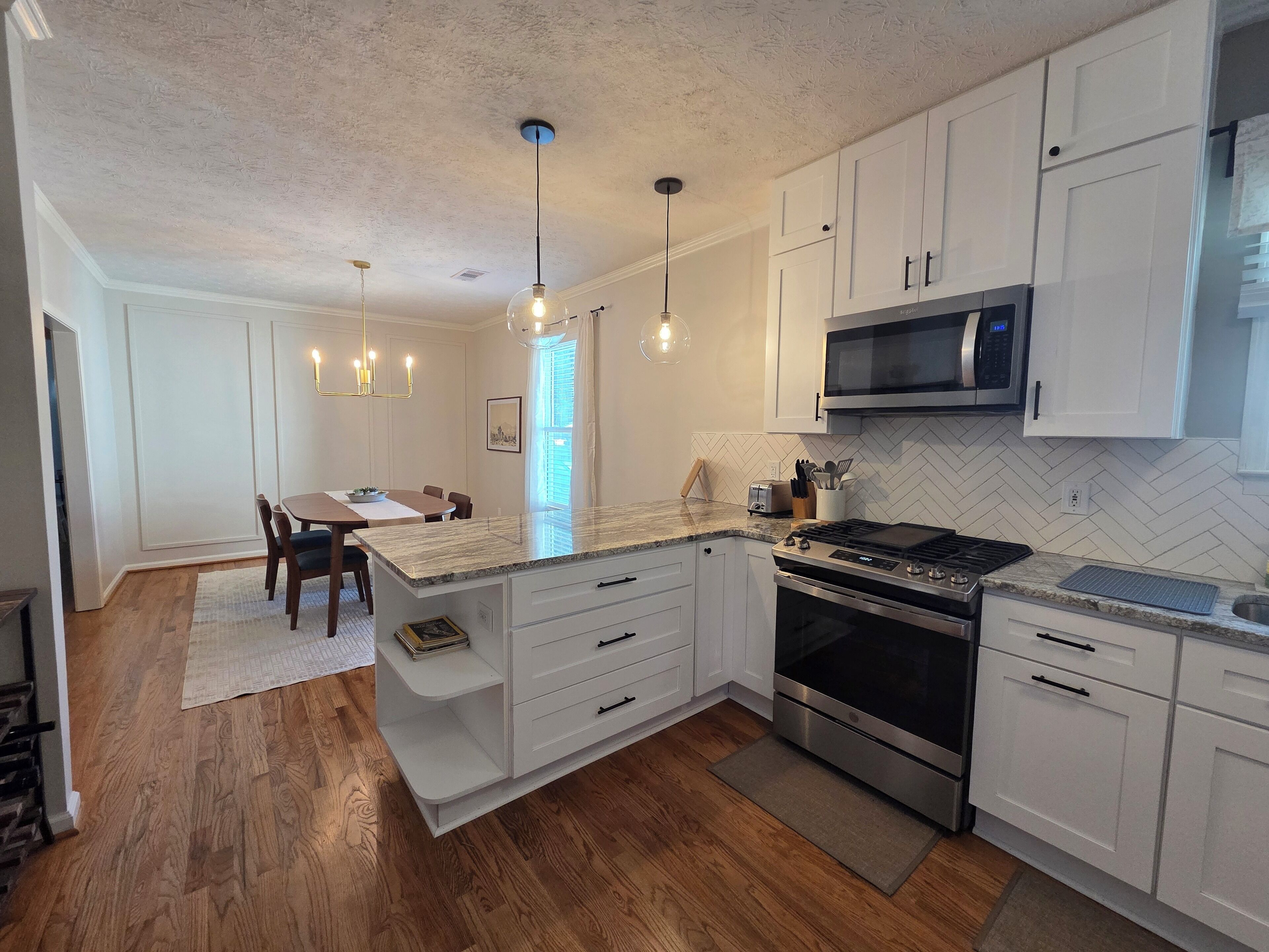 A modern kitchen with white cabinetry, a built-in stove, and a microwave.