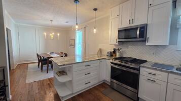 A modern kitchen with white cabinetry, a built-in stove, and a microwave.