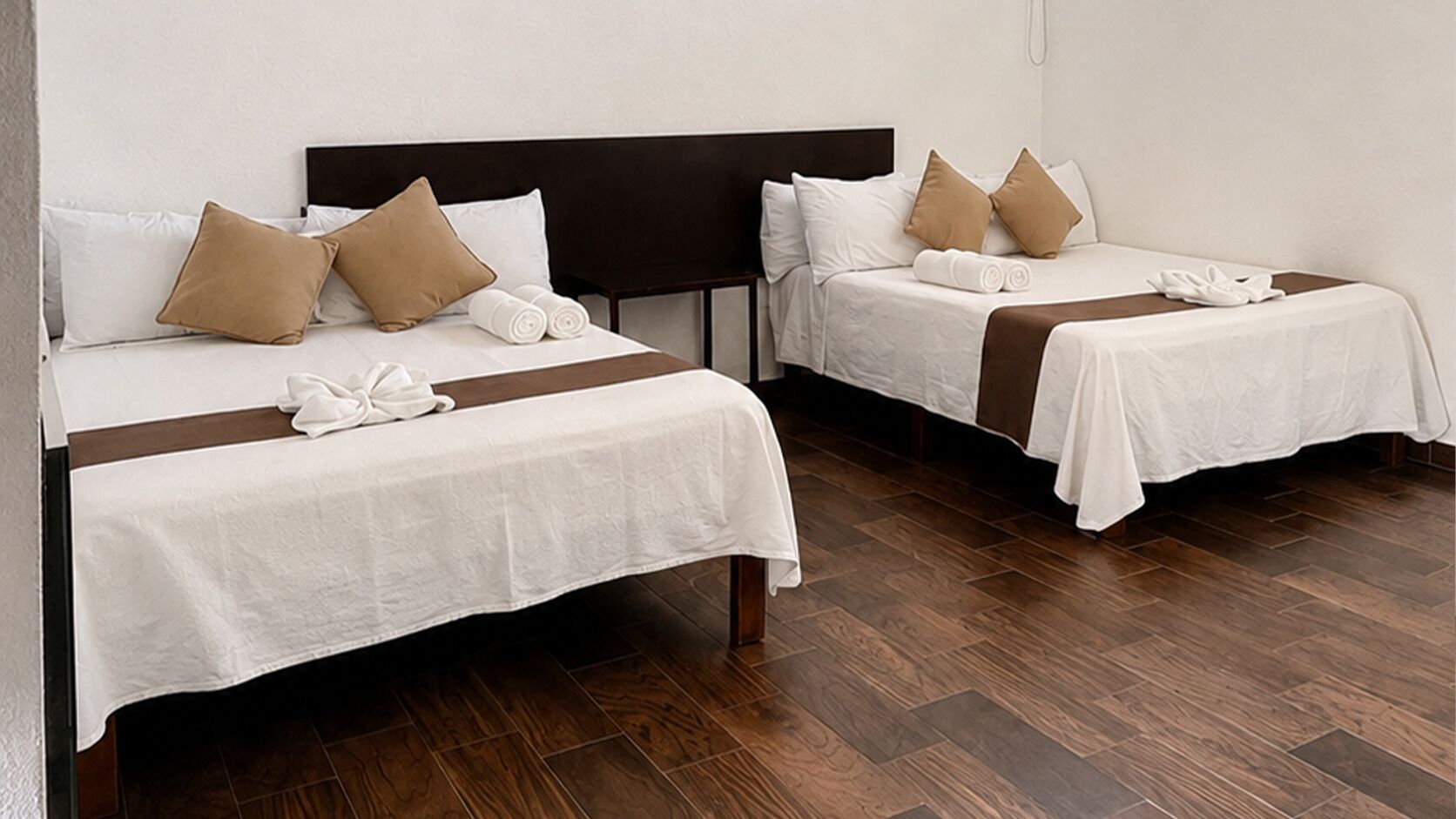 Two single beds with headboards, white bedding, and brown pillows.