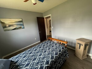 A bedroom with a bed, a wooden bench, a small cabinet, and a painting on the wall.