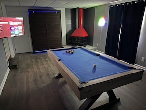 Una mesa de billar con superficie de fieltro azul, una vara roja y una bola blanca.