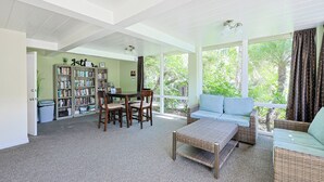 A spacious living area with a large bookshelf, a dining table, and a comfortable seating area with a view of the outdoors. - Come Stay at This Coastal Comfort in the Heart of Socal (Oceanside)