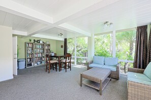 A spacious living area with a large bookshelf, a dining table, and a comfortable seating area with a view of the outdoors. - Come Stay at This Coastal Comfort in the Heart of Socal (Oceanside)