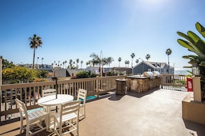 A patio with a round table and chairs, a barbecue grill, and a view of the ocean. - Come Stay at This Coastal Comfort in the Heart of Socal (Oceanside)