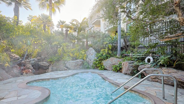 A hot tub surrounded by lush greenery and a stone pathway. - Come Stay at This Coastal Comfort in the Heart of Socal (Oceanside)