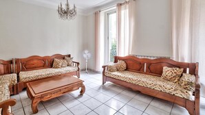 Ein Zimmer mit zwei Holz-Sofas, einem Holztisch, einem weißen Ventilator und einer Kristallleuchter.