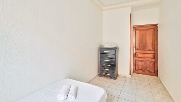 Ein Hotelzimmer mit einem Bett, einer Holztür und einem Aktenschrank.