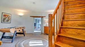 A wooden staircase leading to an upper level, a foosball table, a framed artwork, and a lamp on a bedside table. - Unique Norfolk Windmill Retreat for 8 (Dereham)