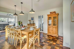 Ein Essbereich mit Holztisch und Stühlen, einer Vitrine mit Glastüren sowie Pendelleuchten.