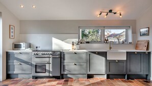 A modern kitchen with a built-in oven, microwave, and a large window above the sink. - Unique Norfolk Windmill Retreat for 8 (Dereham)