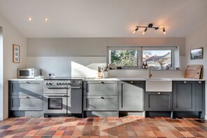 Eine moderne Küche mit Backofen, Mikrowelle und einem großen Fenster über der Spüle.