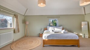 A bedroom with a bed, bedside lamps, a window, and a radiator. - Unique Norfolk Windmill Retreat for 8 (Dereham)