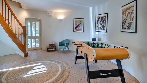 A room with a foosball table, a staircase, and framed artwork on the walls. - Unique Norfolk Windmill Retreat for 8 (Dereham)