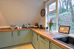 Una cocina con encimera de madera, un fregadero y un ventanal con vista a árboles.