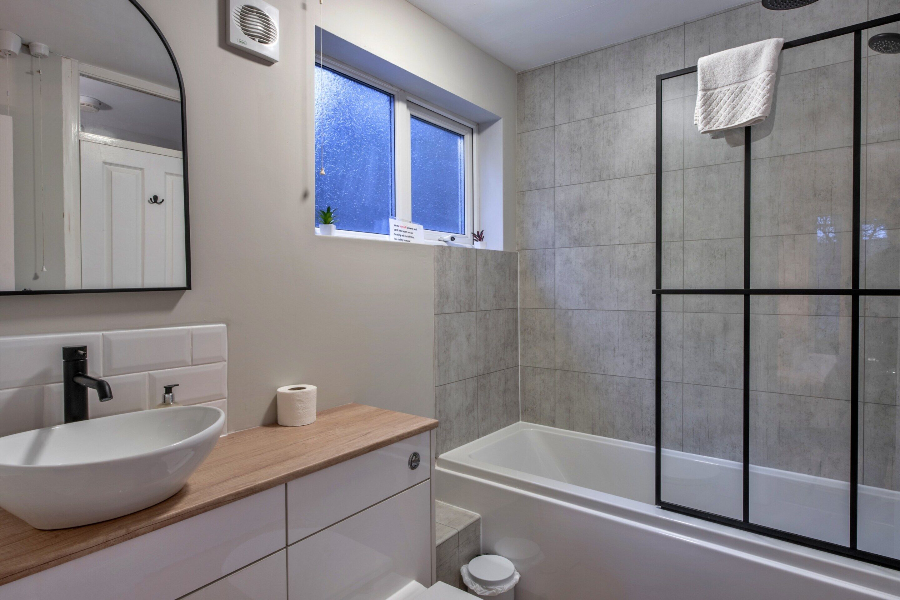 A modern bathroom with a white sink, a bathtub, and a shower area.