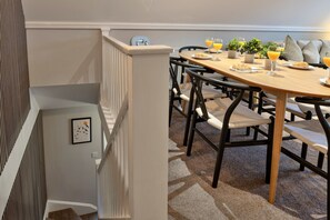Comedor con mesa de madera, sillas y productos para el desayuno como croissants y jugo de naranja.