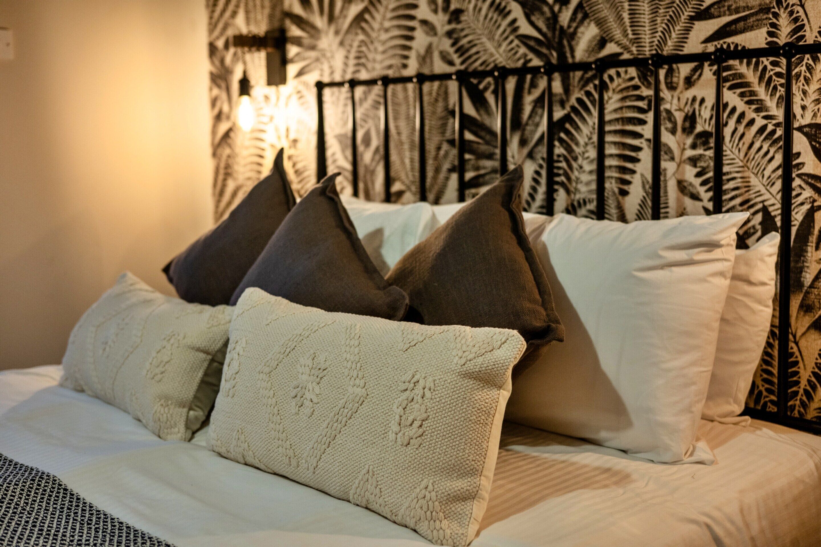 A bed with a patterned headboard, multiple pillows, and a textured blanket.