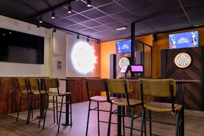 A bar area with multiple dartboards, bar stools, and a large screen displaying a game. - Pine Forest Lodge in Cornwall (Newquay)