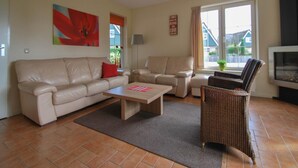 Un salon avec un canapé beige, une table basse en bois et un fauteuil en osier.