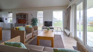 A spacious living area with a sofa set, a television, and a dining table. - Elegant Waterfront Bungalow With Jetty (Makkum)