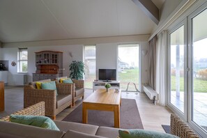 A spacious living area with a sofa set, a television, and a dining table. - Elegant Waterfront Bungalow With Jetty (Makkum)