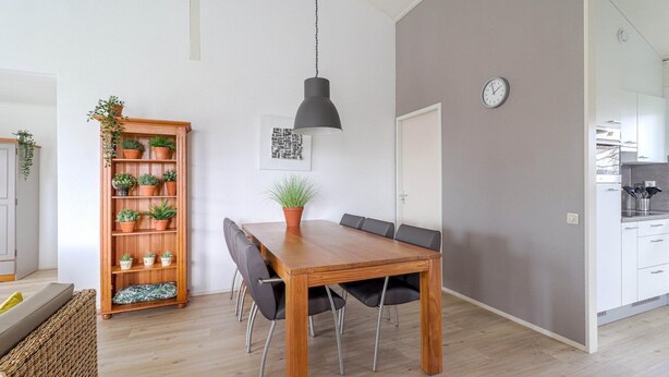 A dining area with a wooden table, black chairs, a potted plant, and a hanging light fixture. - Elegant Waterfront Bungalow With Jetty (Makkum)