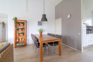 A dining area with a wooden table, black chairs, a potted plant, and a hanging light fixture. - Elegant Waterfront Bungalow With Jetty (Makkum)