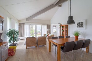 A spacious living area with a dining table, chairs, a sofa, and a large window. - Elegant Waterfront Bungalow With Jetty (Makkum)