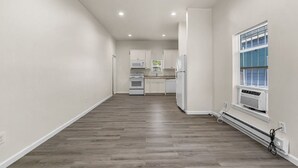 Une cuisine moderne avec des meubles blancs, un four encastré et une fenêtre équipée de stores.