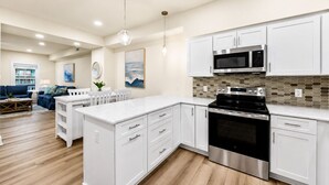 A modern kitchen with white cabinetry, a stainless steel oven, and a microwave. - Spacious 4-bedroom townhome in fabulous Ocean City with AC (Ocean City)
