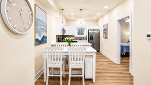 A modern kitchen with white cabinetry, a stainless steel refrigerator, and a dining area with a white table and chairs. - Spacious 4-bedroom townhome in fabulous Ocean City with AC (Ocean City)