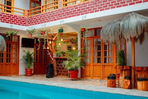 A poolside area with a brick wall, wooden doors, and potted plants. - Majus House  (Los Organos)