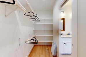 A narrow hallway with a white radiator, a wooden floor, and a white door leading to a bathroom with a mirror and a sink.